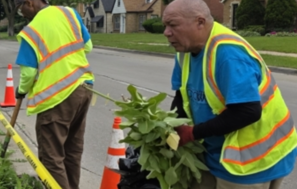 Two men in reflective vests carrying yard waste on the side of a street working for the Vet Corps from the Great Lakes Community Conservation Corps and showing the transition from military to civilian life
